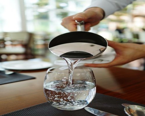 A person pouring a glass of fresh water at their desk